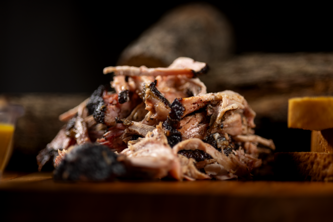 Tasty pulled pork sandwiches topped with creamy macaroni in a London market setting.